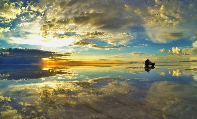 Reflejo del cielo sobre agua y un automóvil en Salar de Uyuni