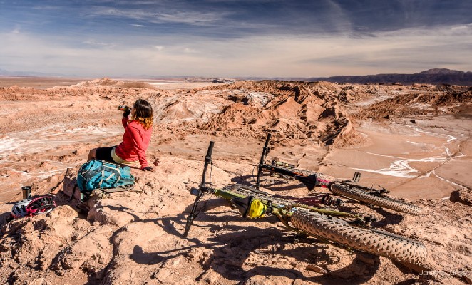 Viajante bebe água e descansa ao lado de sua bicicleta no Atacama